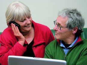 זוג מתבונן בלפטופ בזמן שיחת טלפון